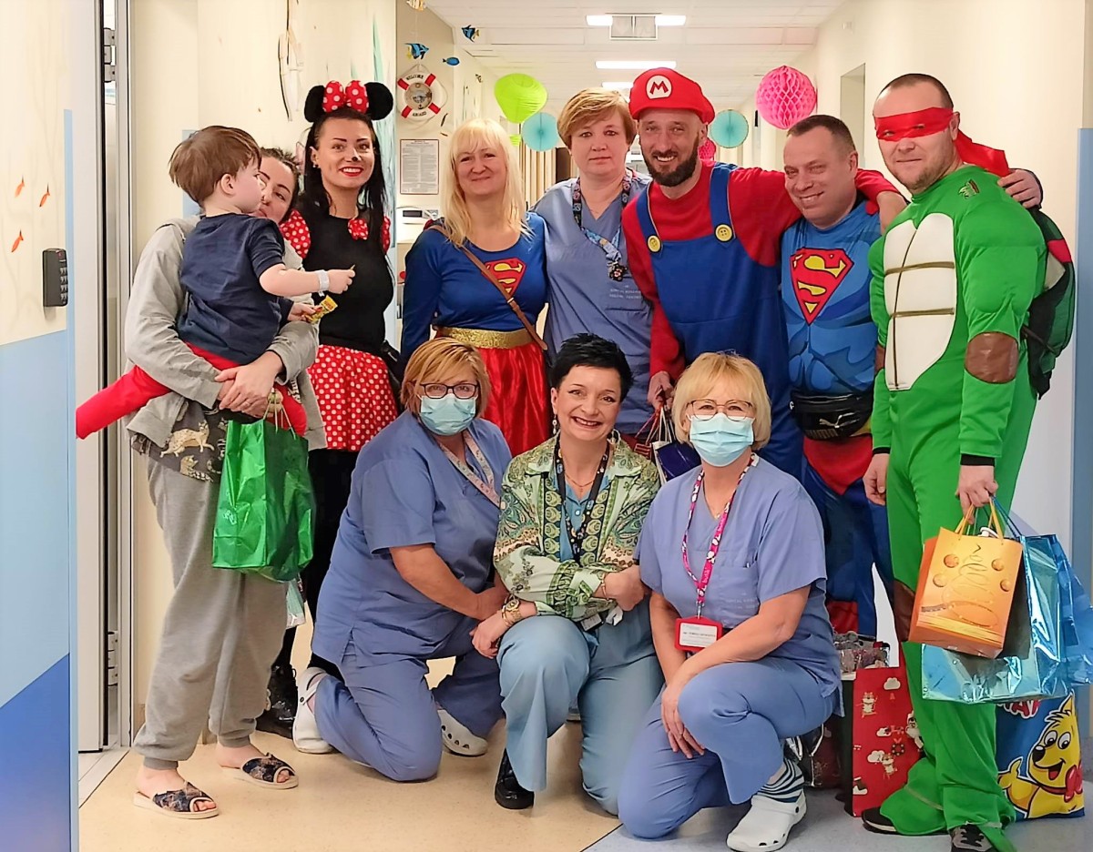Grupa osób - pielęgniarki, osoby przebrane za superbohaterów i mały pacjent